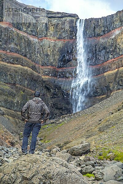 Ein junger Mann betrachtet eines der Wunder Islands  den Wasserfall Hengifoss