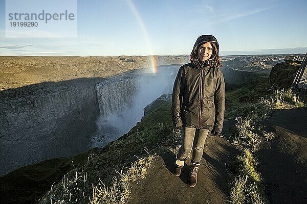 Eine junge Frau schaut sich den Dettifoss Wasserfall in Island an. Der größte Wasserfall in der europäischen Gemeinschaft