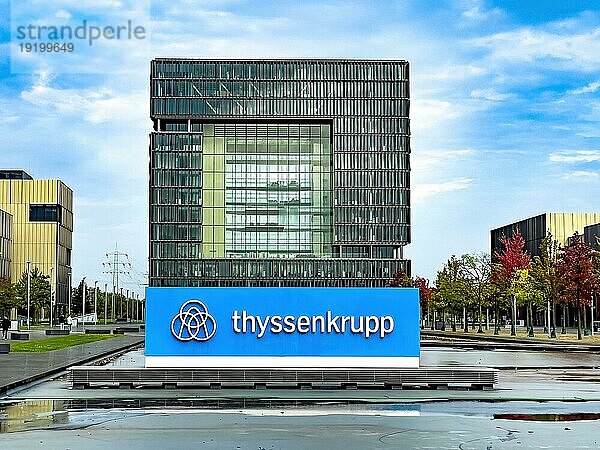 Blick auf im Hintergrund Hauptverwaltung in Form von Würfel Cube von Stahlriese Firma von Stahlproduktion Hersteller von Stahl thyssenkrupp Thyssen Krupp im Vordergrund Logo und Schriftzug  Essen  Nordrhein-Westfalen  Deutschland  Europa