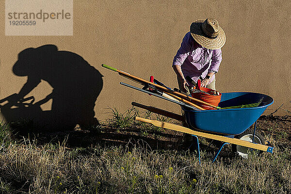 Ältere Frau mit Gartengeräten im Wüstengarten