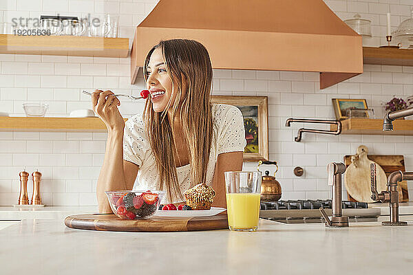 Lächelnde Frau genießt gesundes Frühstück in der Küche