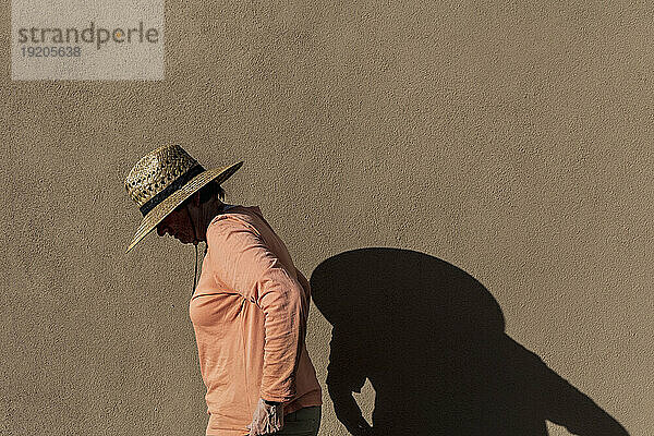 Ältere Frau mit Hut wirft Schatten an die Wand
