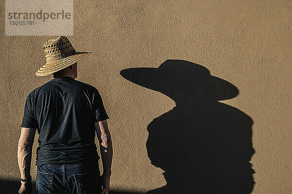 Man in hat casting shadow on wall