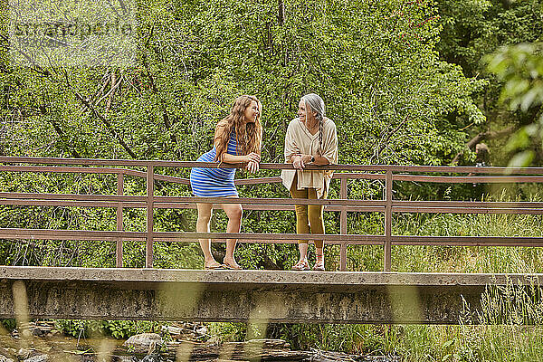 Mutter und erwachsene Tochter stehen auf der Brücke