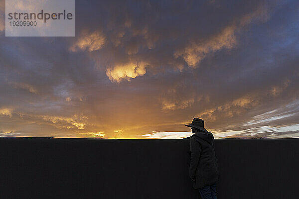 Silhouette eines Mannes mit Hut  der den Sonnenuntergang betrachtet