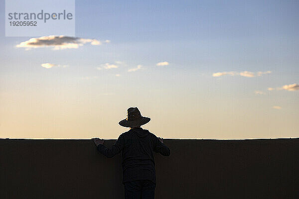 Silhouette eines Mannes mit Hut  der den Sonnenuntergang betrachtet