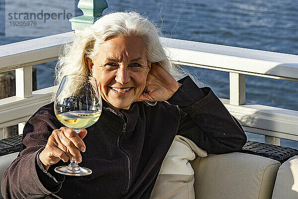 Porträt einer lächelnden älteren Frau  die sich bei einem Glas Wein entspannt