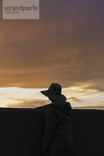 Silhouette eines Mannes mit Hut  der den Sonnenuntergang betrachtet