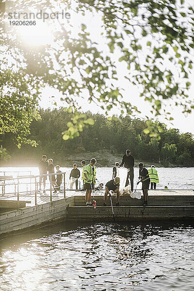 Jungen sammeln Müll vom Steg am See