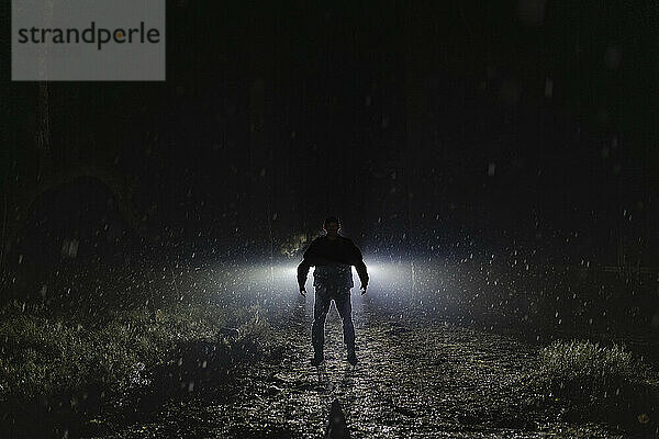 Silhouette eines Dämons  der nachts während der Regenzeit im Wald steht