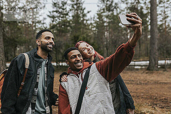 Fröhliche  gemischtrassige Freunde  die im Garten ein Selfie mit dem Smartphone machen