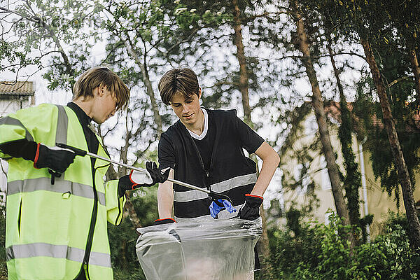 Jungen sammeln Plastik im Müllsack