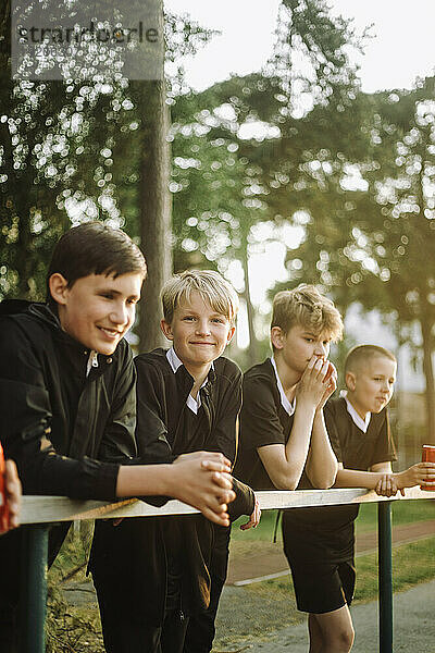 Jungen lehnen sich an Geländer  während sie sich ein Spiel ansehen