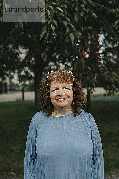 Porträt einer lächelnden älteren Frau  die im Park steht