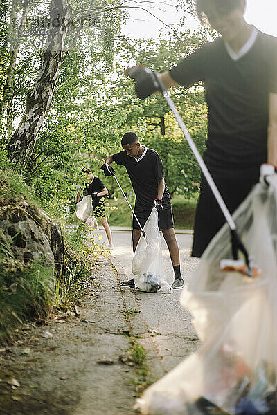 Teenager sammeln unterwegs Plastik in Müllsäcken