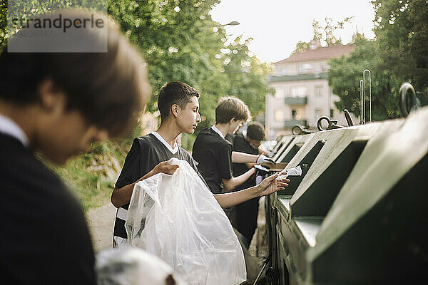 Jungen werfen Plastikmüll in den Papierkorb