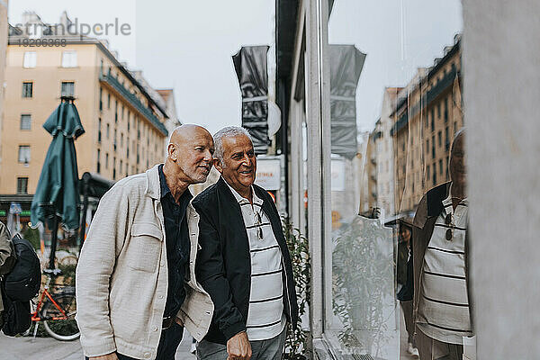 Ältere männliche Freunde diskutieren miteinander beim Schaufensterbummel auf der Straße