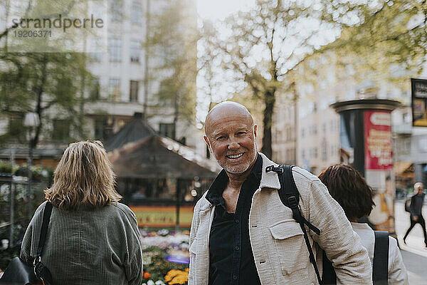 Porträt eines lächelnden älteren Mannes mit rasiertem Kopf auf der Straße