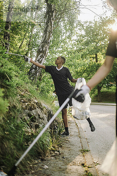 Teenager pflücken Plastik von Pflanzen