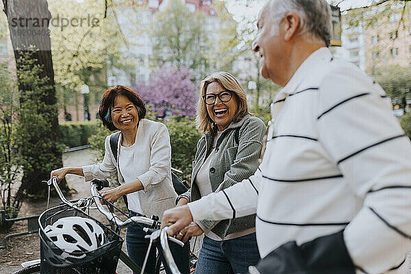 Happy male and female senior friends with bicycles at park