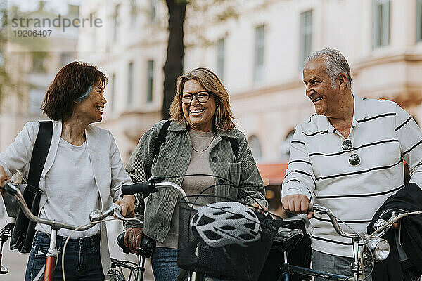 Glückliche männliche und weibliche ältere Freunde mit Fahrrädern auf dem Fußweg