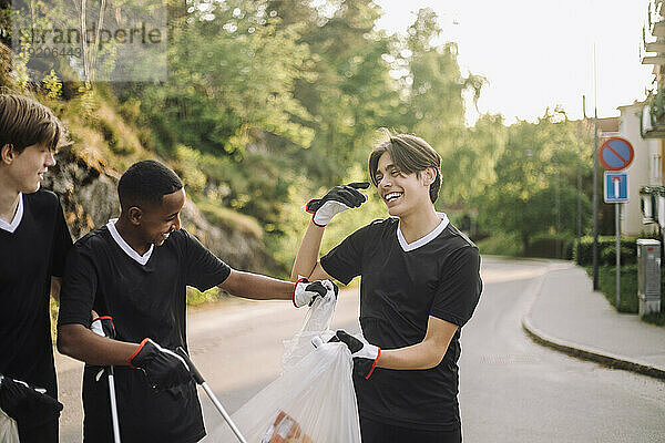 Fröhliche Teenager mit Müllsäcken unterwegs