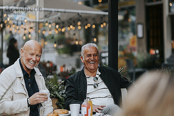Glücklicher älterer Mann  der mit Freunden im Straßencafé genießt