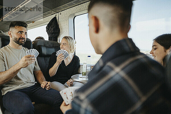 Familie genießt und hat Spaß beim Kartenspielen im Zug