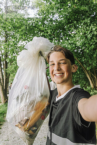 Porträt eines glücklichen Teenagers  der einen Müllsack zeigt