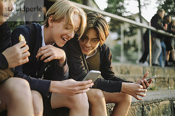 Glückliche Teenager  die ihr Smartphone teilen