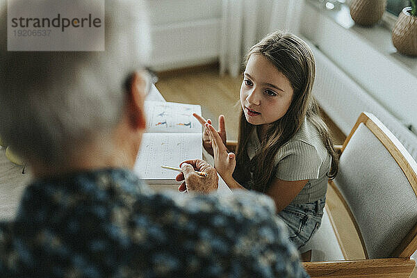 Mädchen macht Hausaufgaben mit Großvater zu Hause