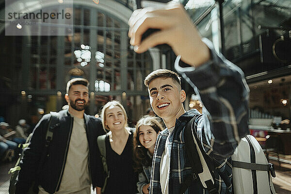 Fröhlicher Junge  der am Bahnhof ein Selfie mit seiner Familie macht