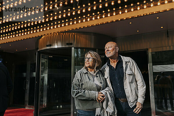 Lächelnde männliche und weibliche ältere Freunde stehen vor dem Kino