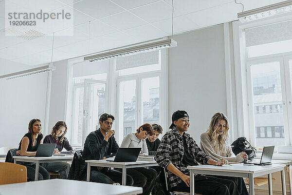 Gemischtrassige männliche und weibliche Studenten sitzen am Schreibtisch im Klassenzimmer