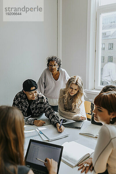 Lehrer steht hinter Schülern im Klassenzimmer