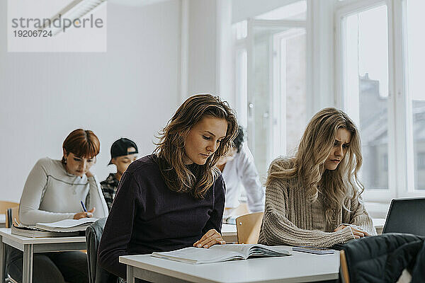 Junge Studentinnen lernen am Schreibtisch im Klassenzimmer