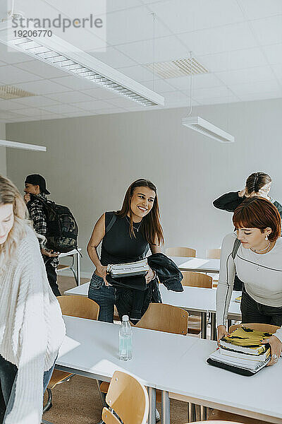 Lächelndes Teenager-Mädchen mit Freunden im Klassenzimmer