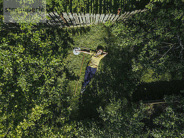Luftaufnahme einer Frau mittleren Alters  die sich auf einer Wiese im Garten ausruht