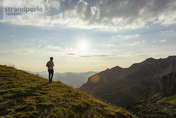 Germany  Bavaria  Oberstdorf  man on a hike in the mountains looking at view at sunset