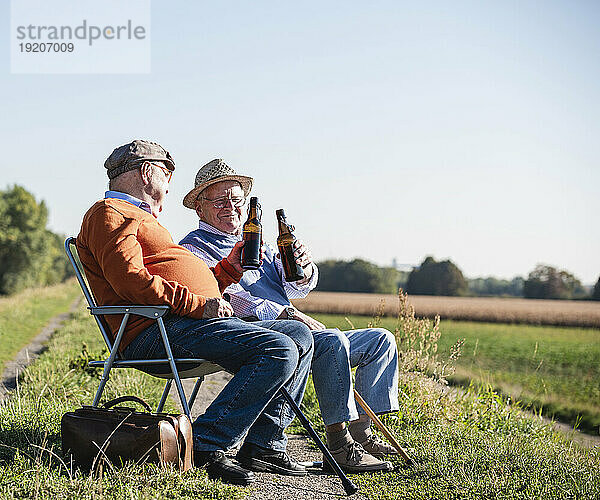 Zwei alte Freunde sitzen auf den Feldern  trinken Bier und reden über alte Zeiten