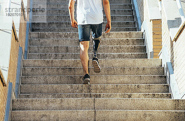 Junger Mann mit Beinprothese geht die Treppe hinauf