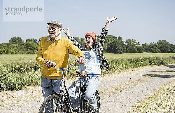 Fröhlicher älterer Mann mit Enkelin genießt das Fahrradfahren