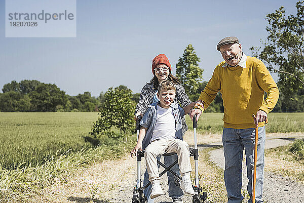 Glücklicher Großvater mit Enkel  der auf einem Rollator sitzt