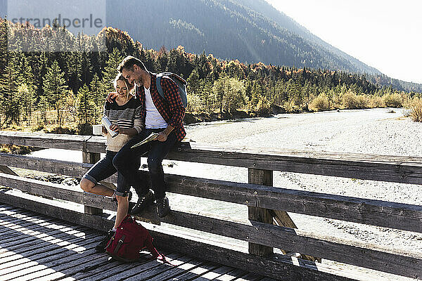 Österreich  Alpen  Paar auf einer Wandertour macht Pause auf einer Brücke