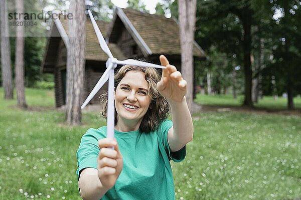 Verspielte Frau hält Windturbinenmodell im Wald