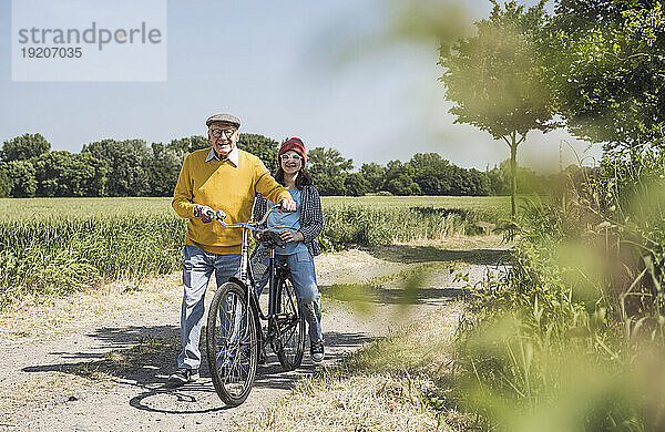 Glücklicher älterer Mann mit Enkelin  die auf dem Fahrrad sitzt