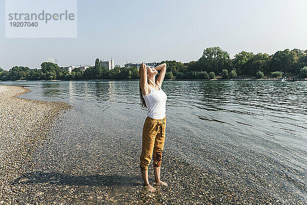 Glückliche junge Frau  die entspannt im Wasser eines Flusses steht