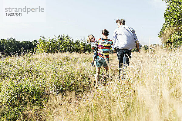 Glückliche Familie  die an einem schönen Sommertag am Flussufer spaziert