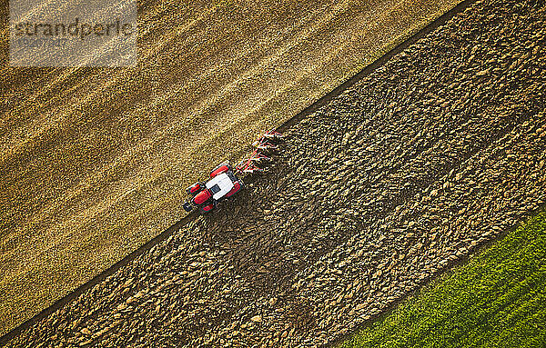 Farmer using tractor and plowing land at sunrise