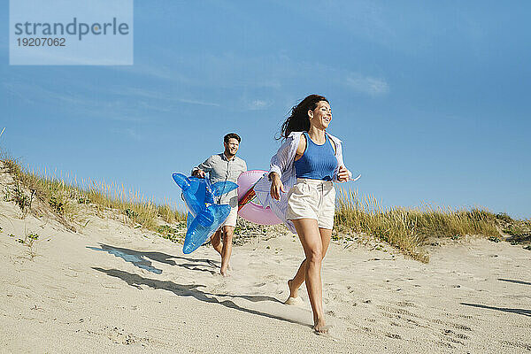 Glückliche Frau und Mann laufen an einem sonnigen Tag am Strand